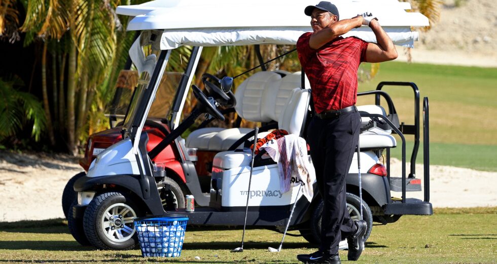 Wearing Sunday red, Tiger Woods hits balls yet again during Hero